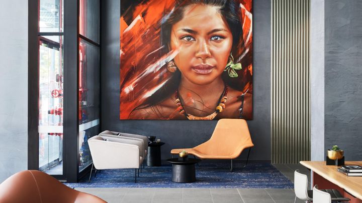 A blue-tinged hotel lobby area with a large portrait on the wall showing a woman